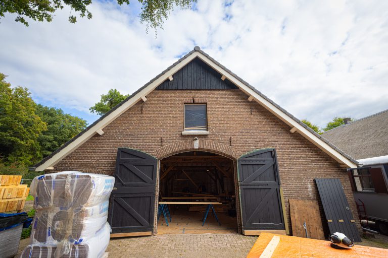 Foto van woonboerderij met grote openstaande schuurdeuren.