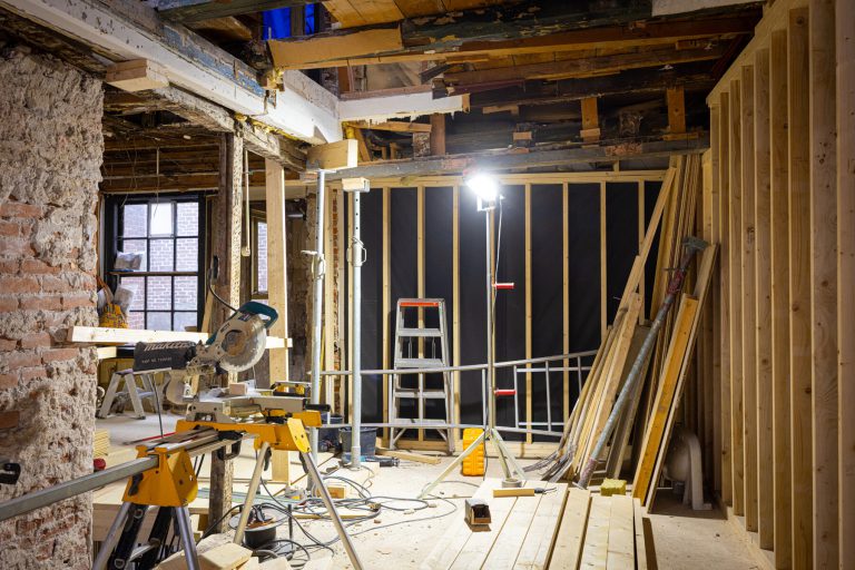 Foto tijdens renovatiewerkzaamheden met nieuwe houten wanden en houten ondersteuningen.